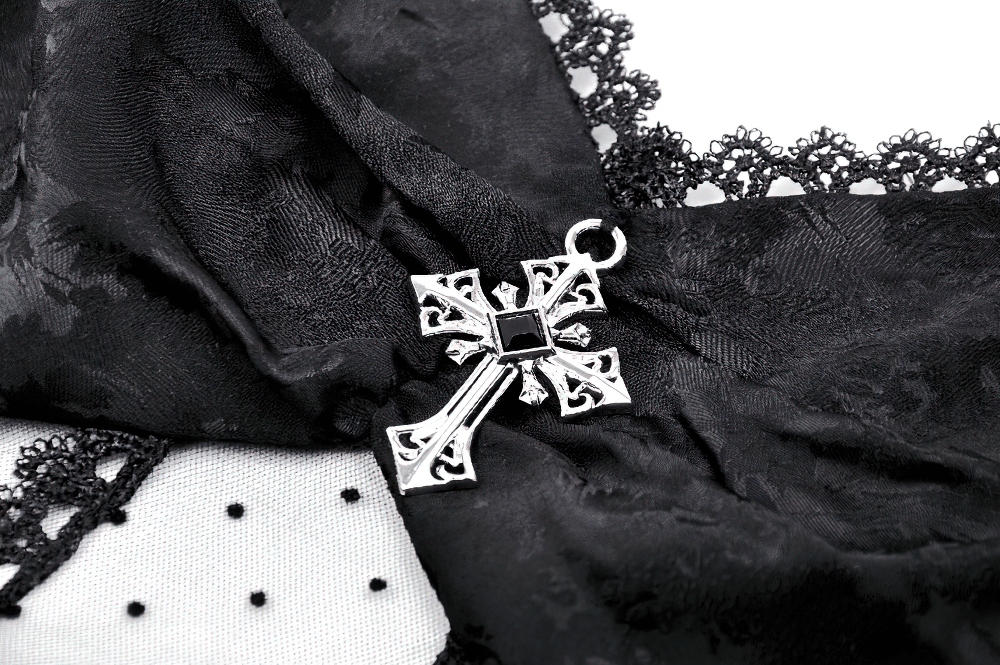 Close-up of gothic lace fabric featuring a silver cross pendant, highlighting intricate details and dark elegance.