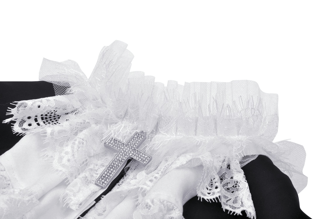 Close-up of gothic lace detailing and silver cross on a black cropped jacket with white ruffle collar.