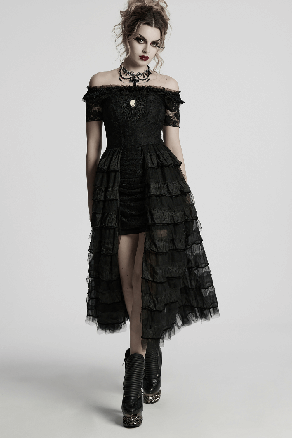 Gothic model in elegant off-shoulder black dress with layered ruffles and bold accessories, exuding vintage charm.