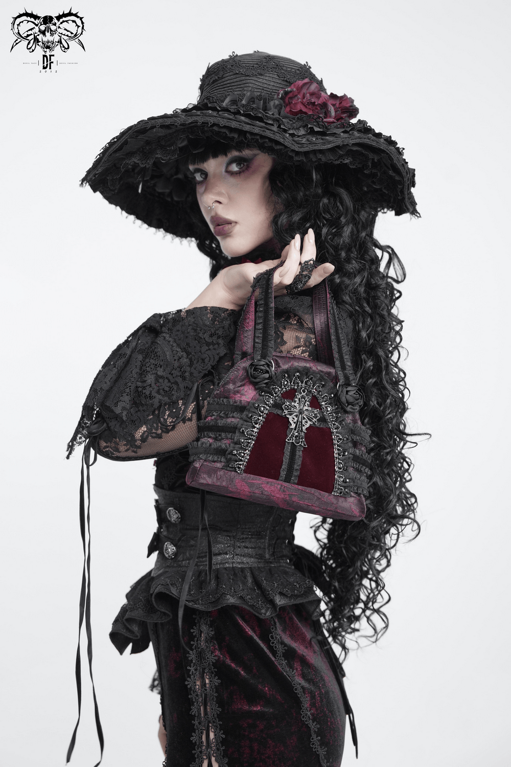 Gothic Cross Velvet Handbag with Ruffle Trim Details held by a model in a Victorian gothic outfit.