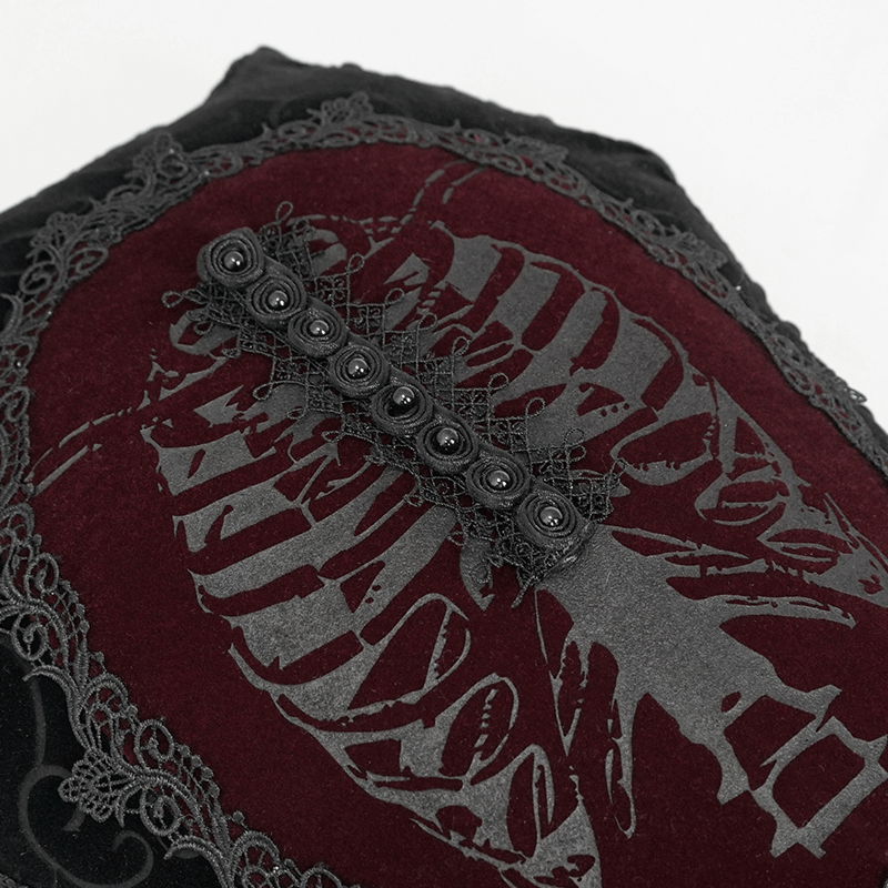 Close-up of gothic coffin-shaped cushion with lace trim and intricate skull design in dark colors.