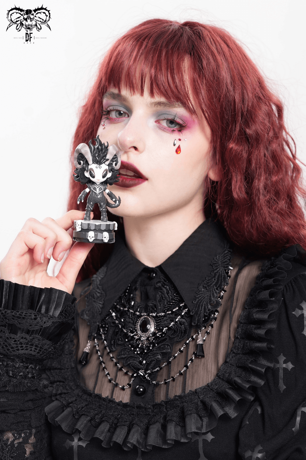 Gothic demon figure with horns held by a model, showcasing edgy fashion and dark aesthetic.