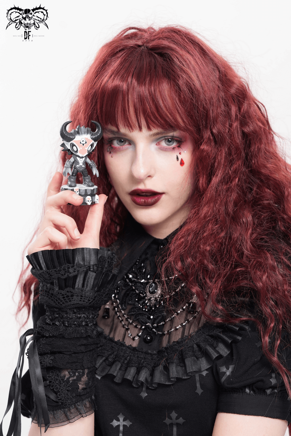 Gothic demon figure with horns held by a model with red hair, showcasing the collectible's unique skull base detail.