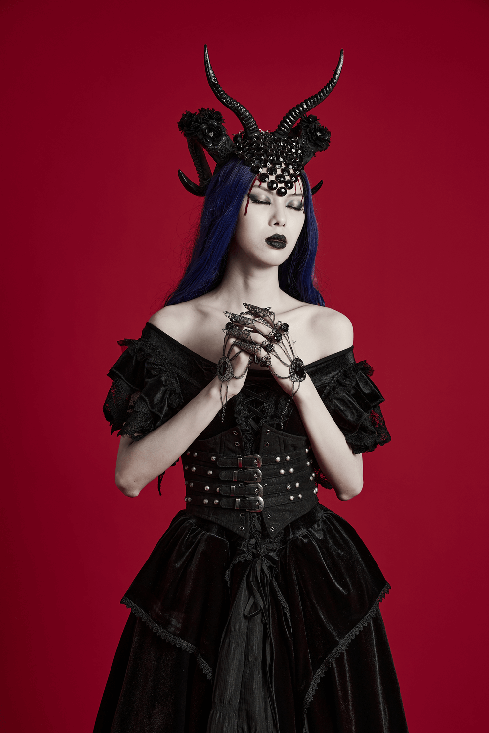 Gothic demon horn headwear with glitter flowers, worn by model against a striking red background.