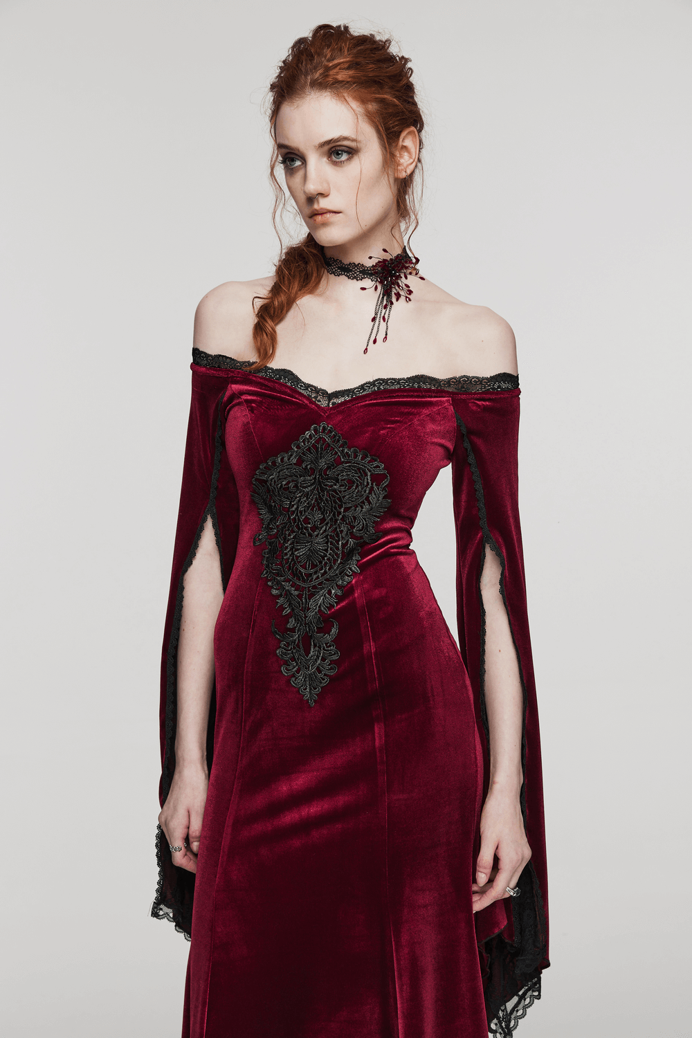 Model in a gothic velvet dress with lace details and a blood-drop choker, showcasing dark fashion elegance.