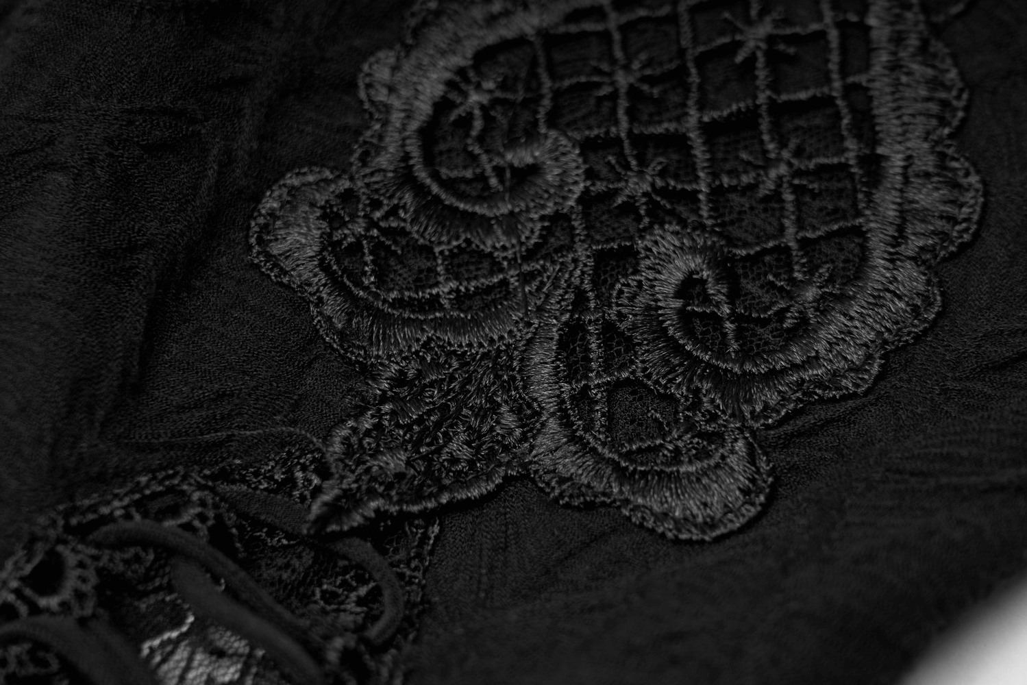 Close-up of intricate black embroidery on gothic elastic leg warmers, showcasing elegant detail and texture.