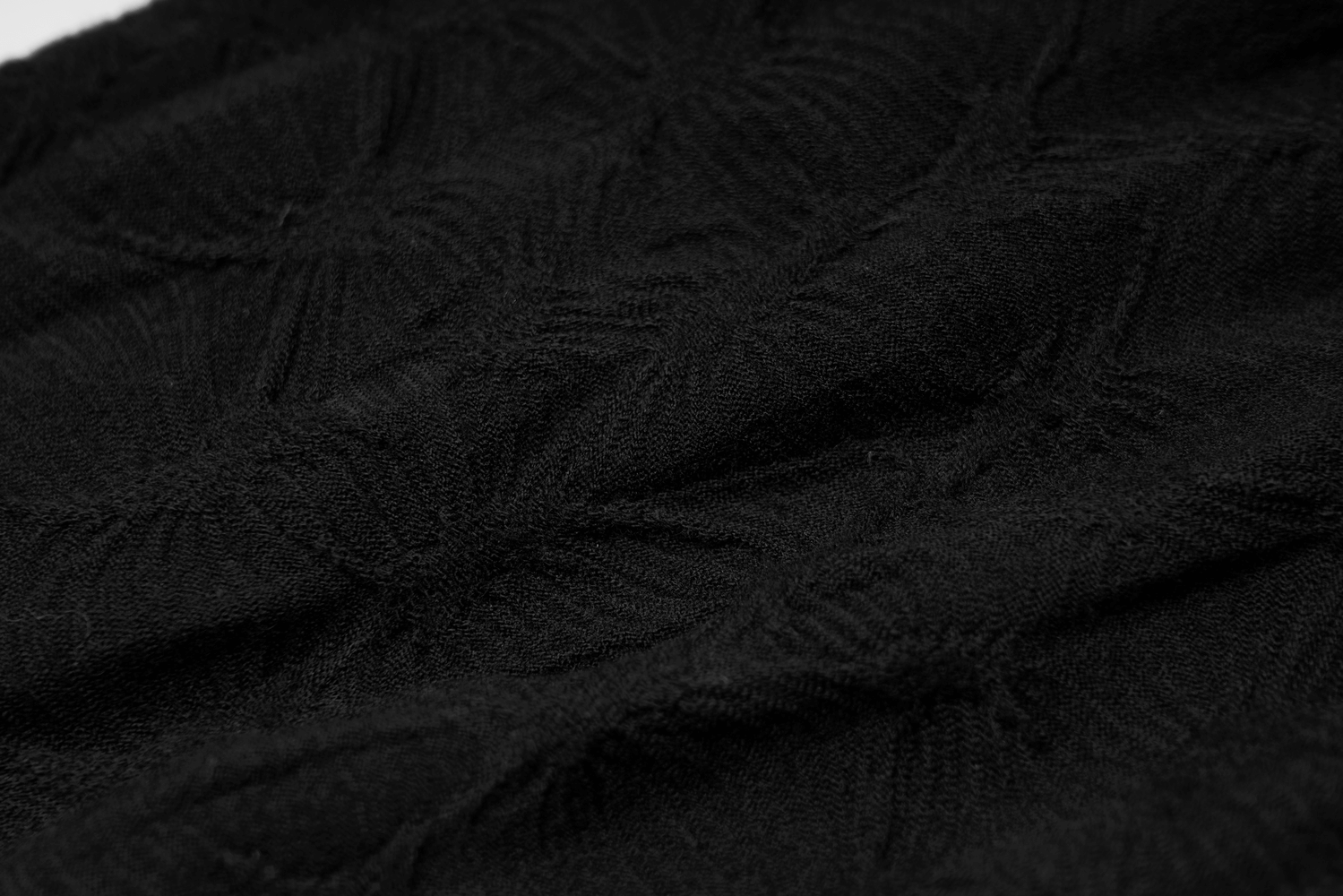 Close-up of black elastic fabric with delicate embroidery pattern, ideal for gothic leg warmers.
