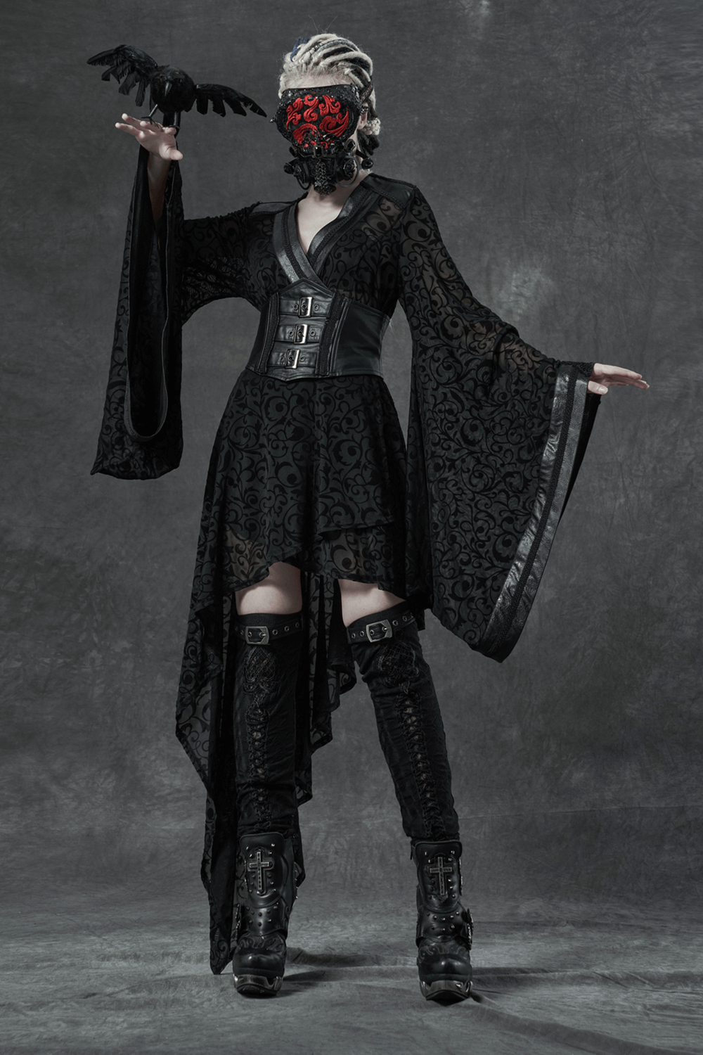 Gothic fashion model wearing a black dress with flowing sleeves and accessories, showcasing dark elegance.