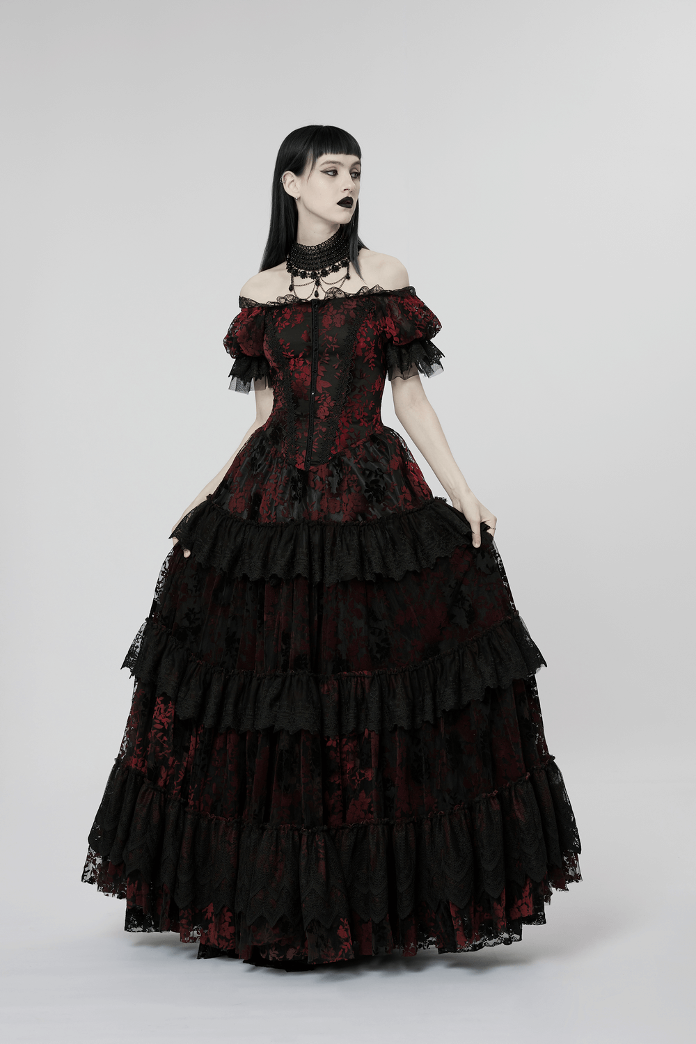 Gothic elegance in a red print gown with flocking details, featuring off-shoulder design and layers of ruffles.