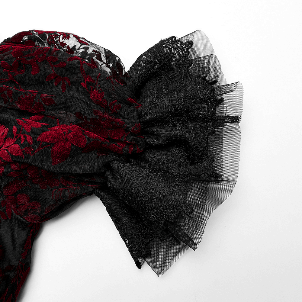 Close-up of Gothic gown fabric showcasing rich red floral flocking on black mesh with lace details.