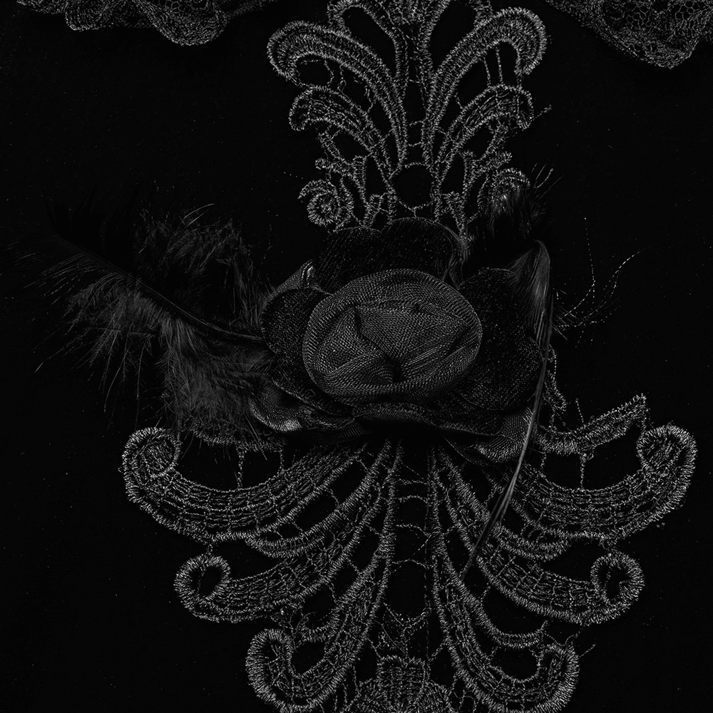 Close-up of intricate black embroidery and feather flower detail on a Gothic velvet dress.