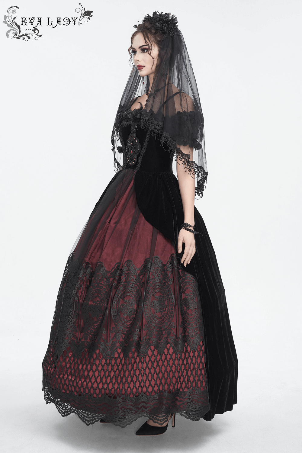 Gothic bridal look featuring a model in a black and red gown with a black veil and romantic flower hair clip.