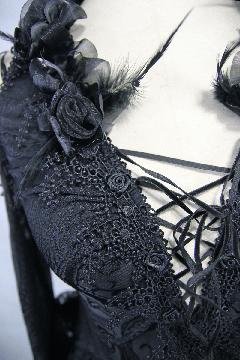 Close-up of a gothic black top featuring intricate floral embroidery, lace details, and ruffled accents.