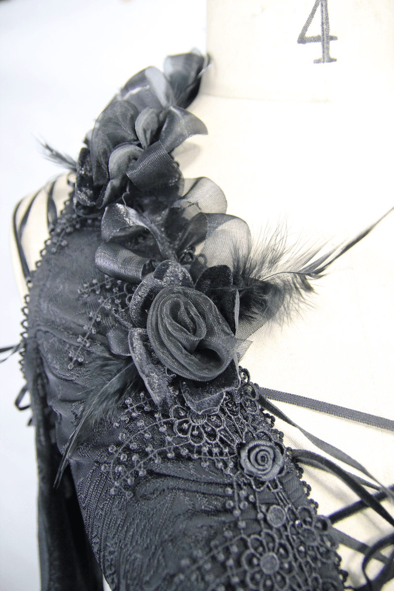 Close-up of a gothic black top featuring intricate embroidered floral details and ruffled trim for a vintage style.
