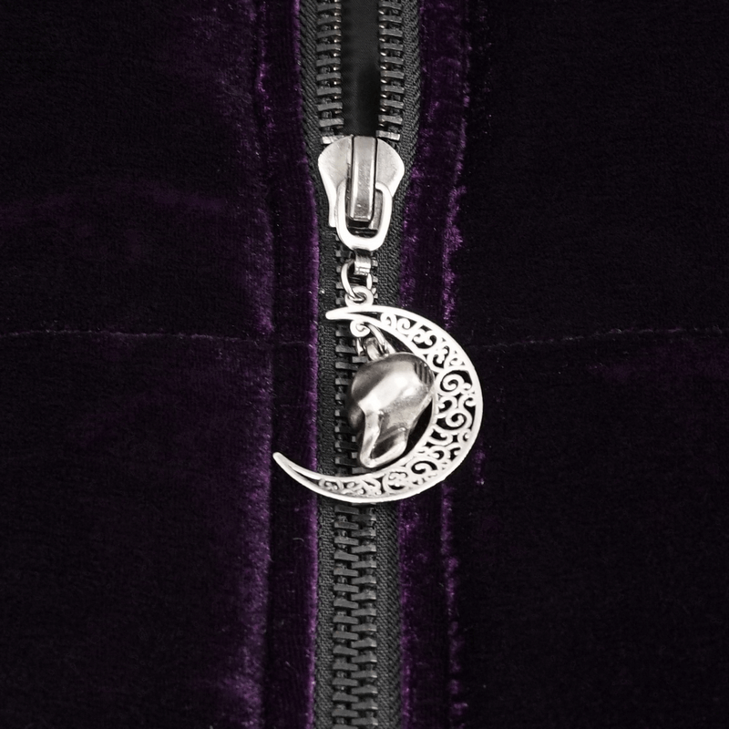 Close-up of silver moon and skull zipper pull on a purple velvet cape, showcasing gothic design details.