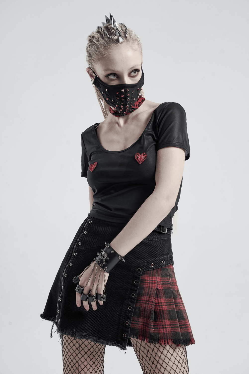 Gothic fashion model in stylish black outfit with plaid skirt and spiked accessories, showcasing edgy punk aesthetics.