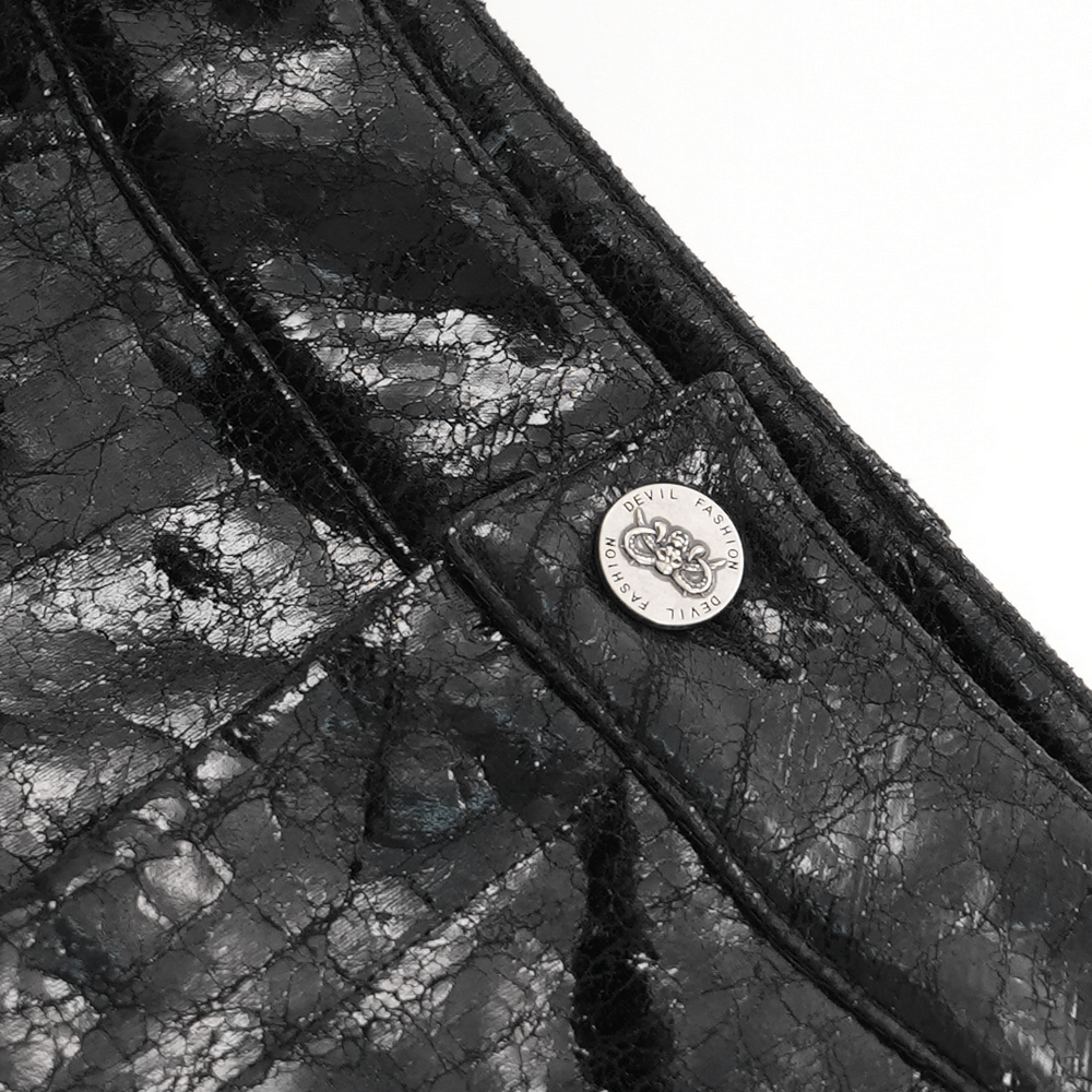 Close-up of Gothic faux leather fabric with metal logo accent, showcasing edgy punk-inspired design details.