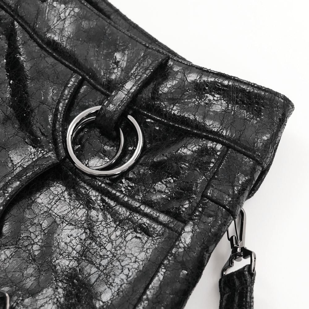 Close-up of gothic faux leather skirt with metal ring and buckle details, showcasing punk-inspired fashion.