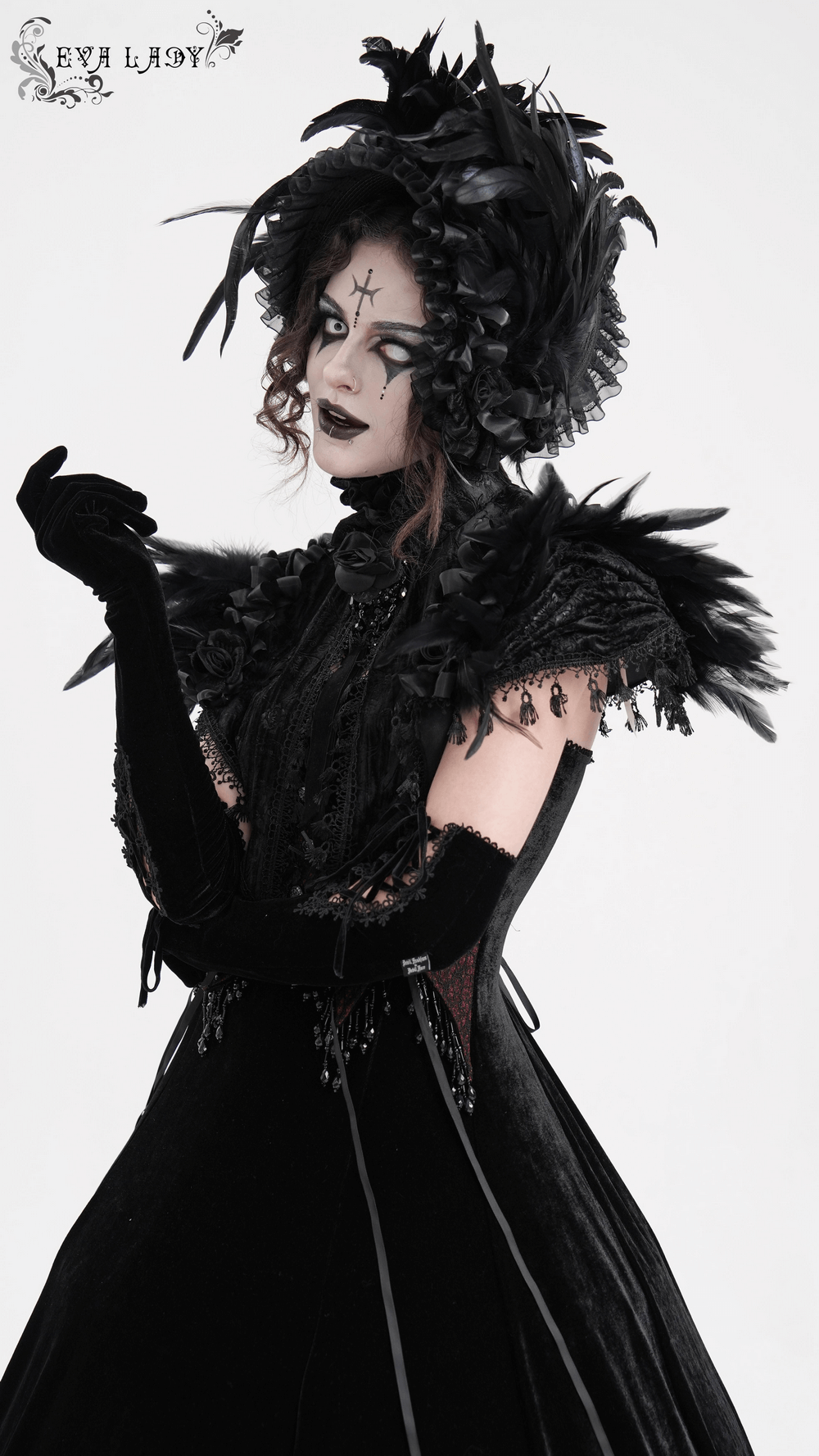 Elegant model in a gothic feathered cape with lace trims, showcasing Victorian style and dramatic black fashion.