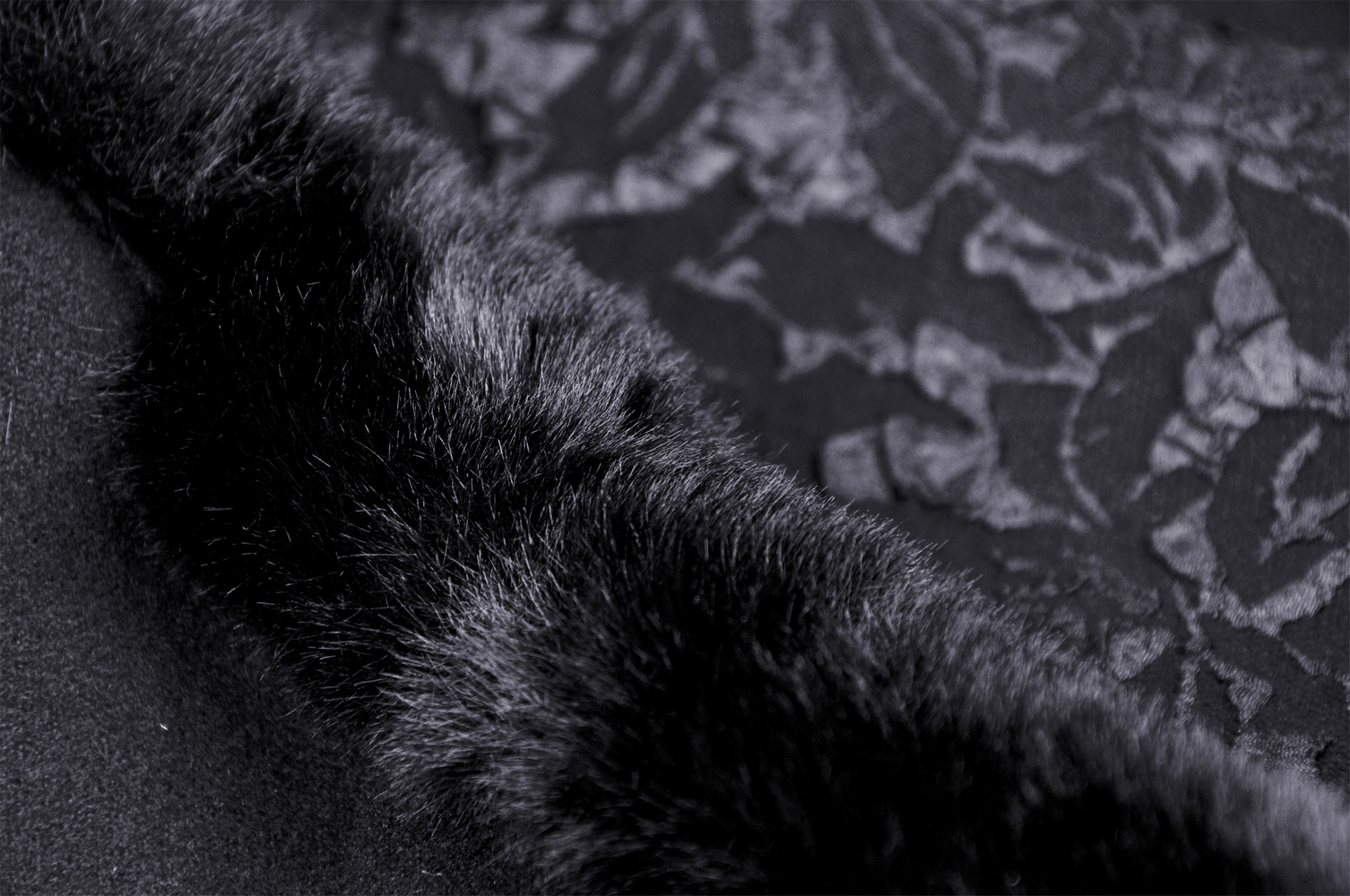 Close-up of luxurious black lace and fur detailing from a gothic women's coat, highlighting elegance and texture.