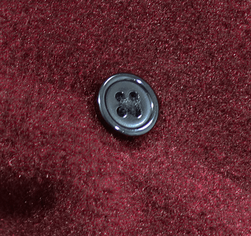 Close-up of a stylish black button on a vintage gothic red coat fabric.