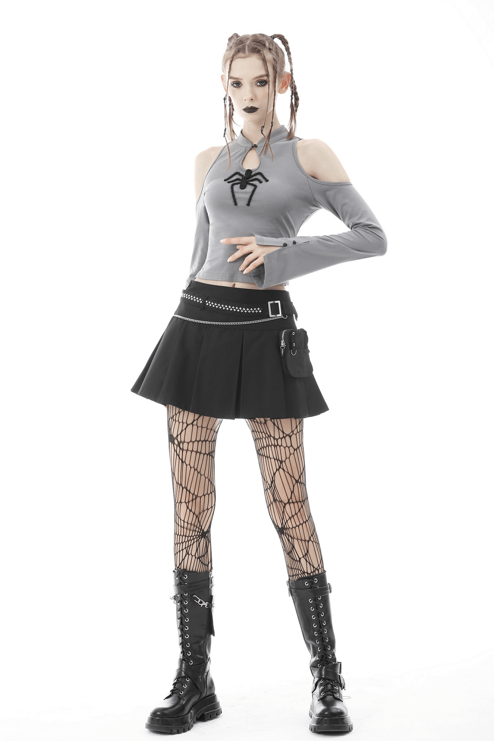 Gothic female model in grey spider top, pleated black mini skirt, fishnet tights, and combat boots.