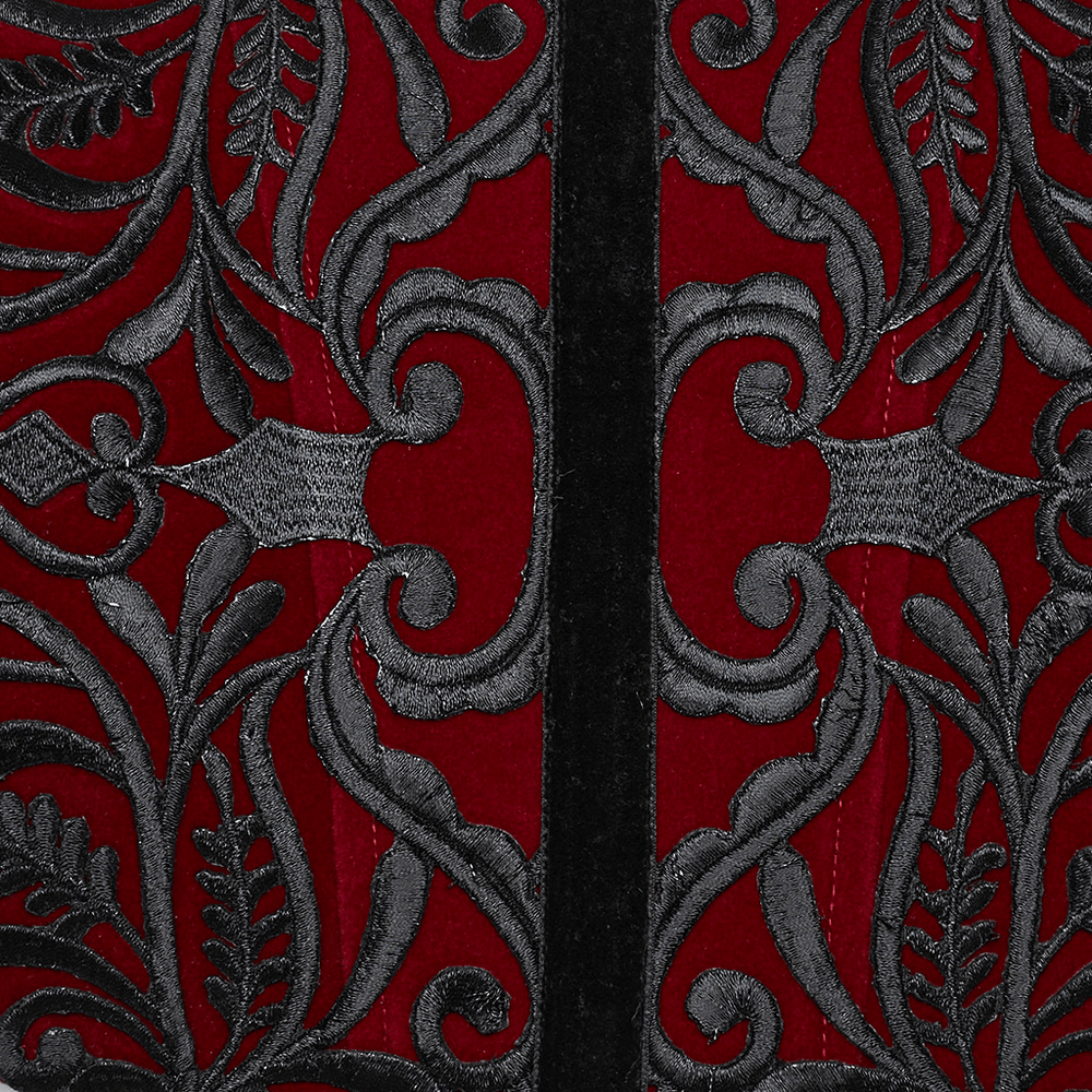 Close-up of gothic velvet corset waistband featuring intricate black floral embroidery on deep red fabric.