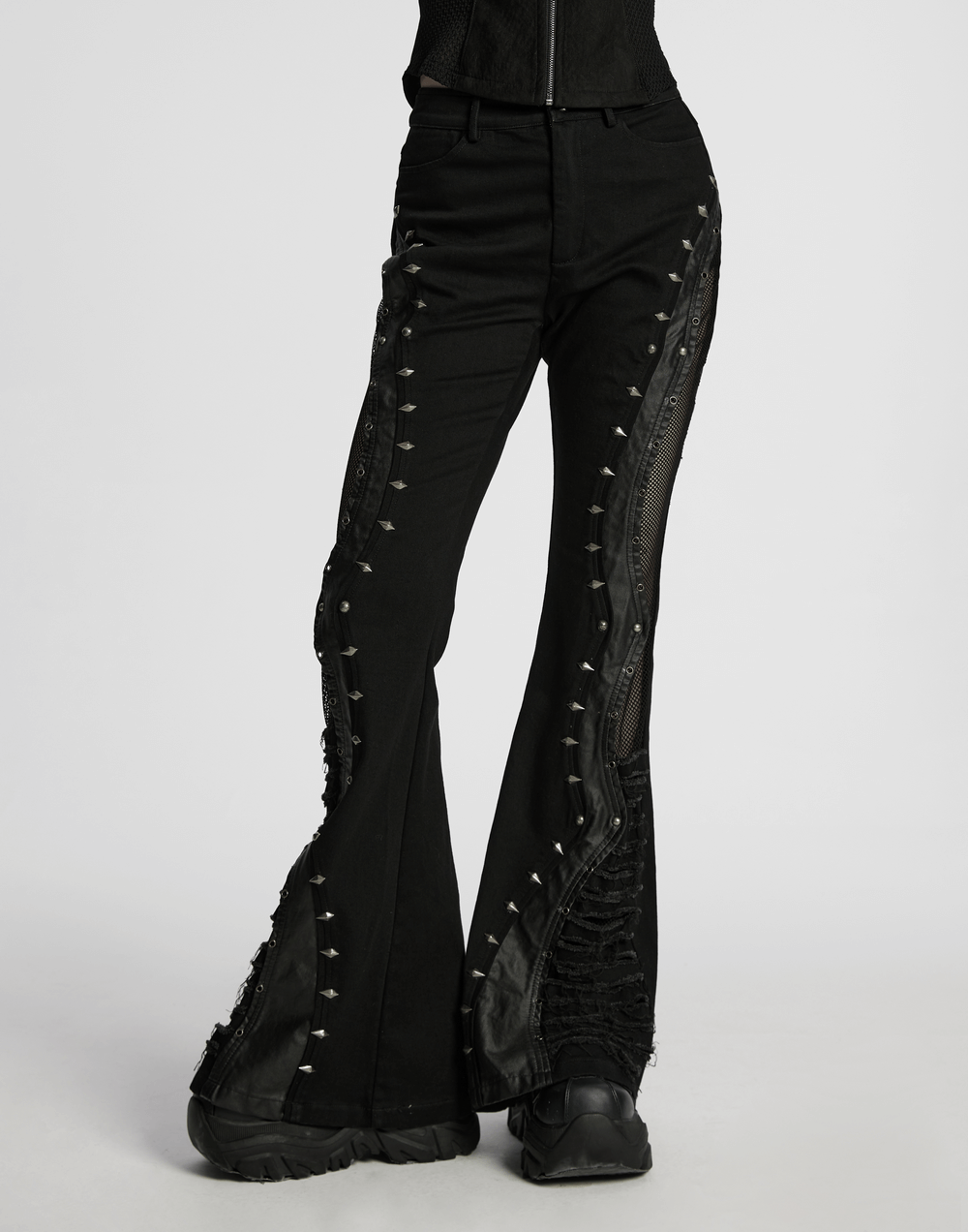 Gothic flared pants featuring studs and mesh panels for a punk rock style, combining denim and faux leather details.