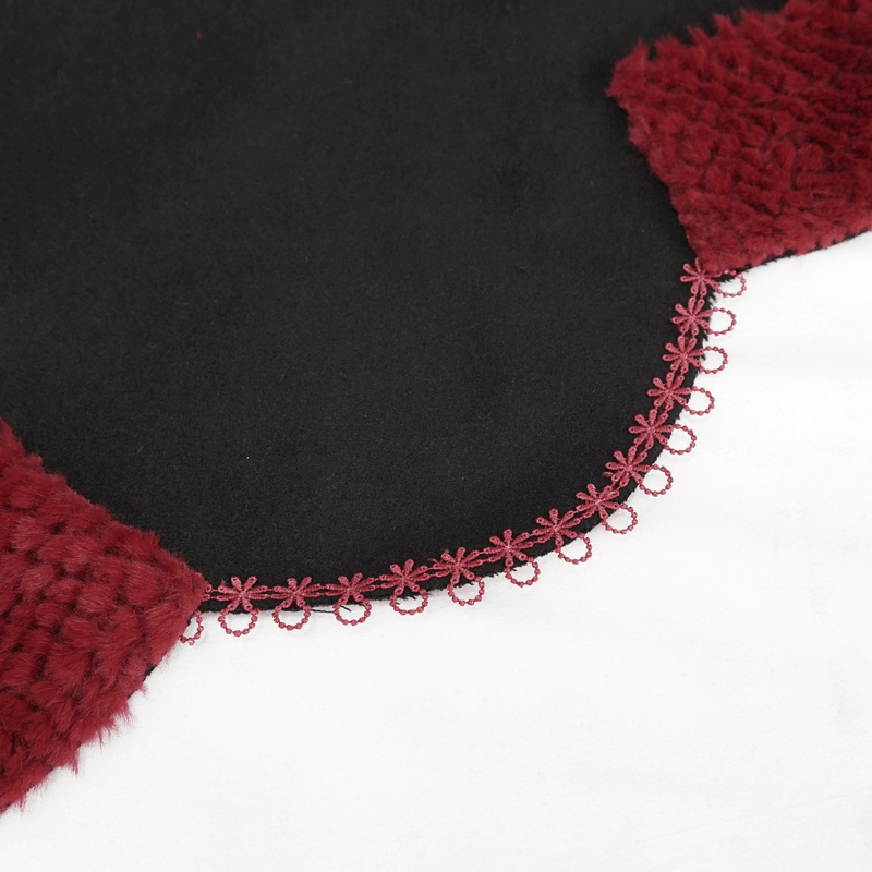 Close-up of black cape edge featuring red floral embroidery and pompons, showcasing gothic style elegance.