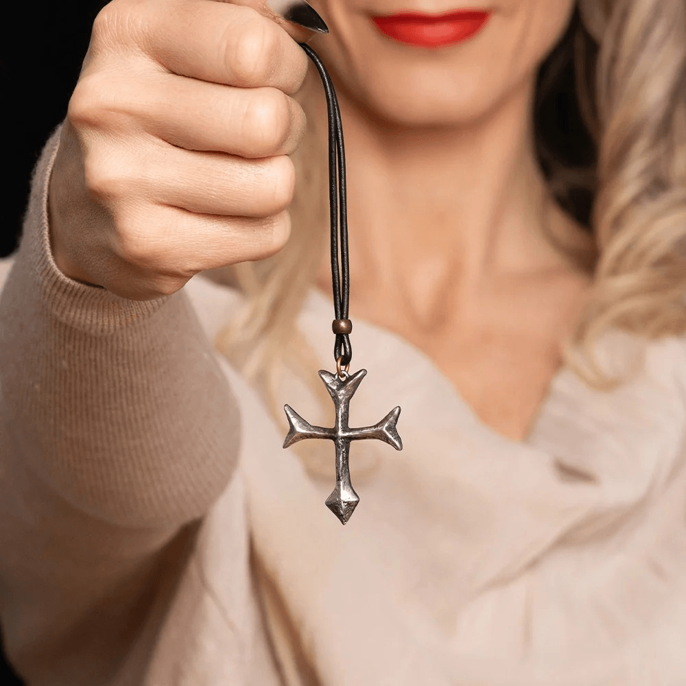 Gothic Fourchee Cross Pewter Pendant Necklace held by a woman, showcasing its unique design and black cord.