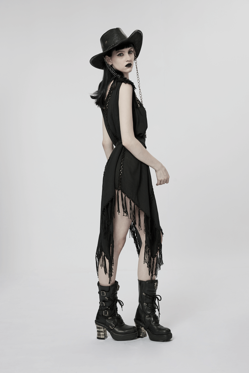 Model wearing a Gothic Fringe V-Neck Dress with boho mesh overlay and black hat, showcasing edgy style and tassel details.