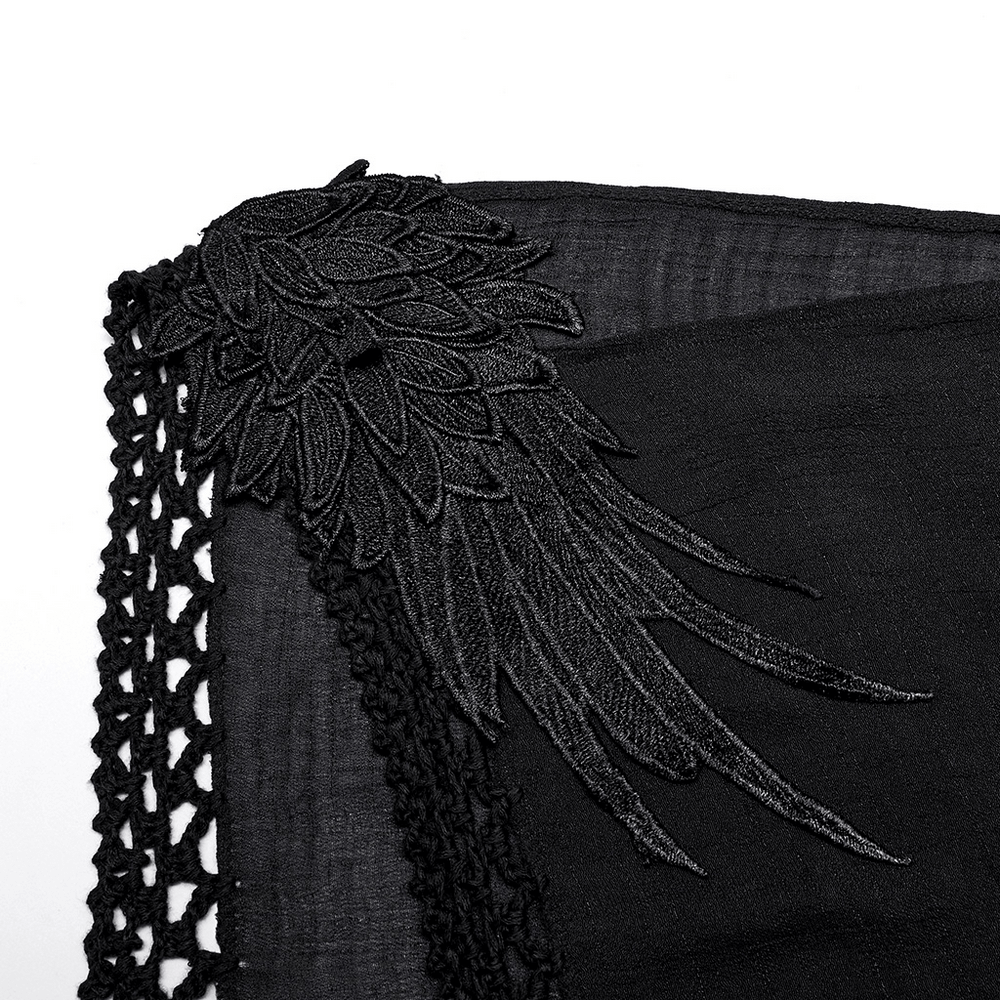 Close-up of black gothic fringe detail on a woven dress, featuring intricate lace and embroidery for a bold style.