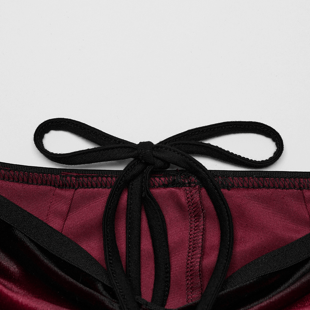 Close-up of burgundy velvet flared pants with black lace trim and tie detail at the waistband.