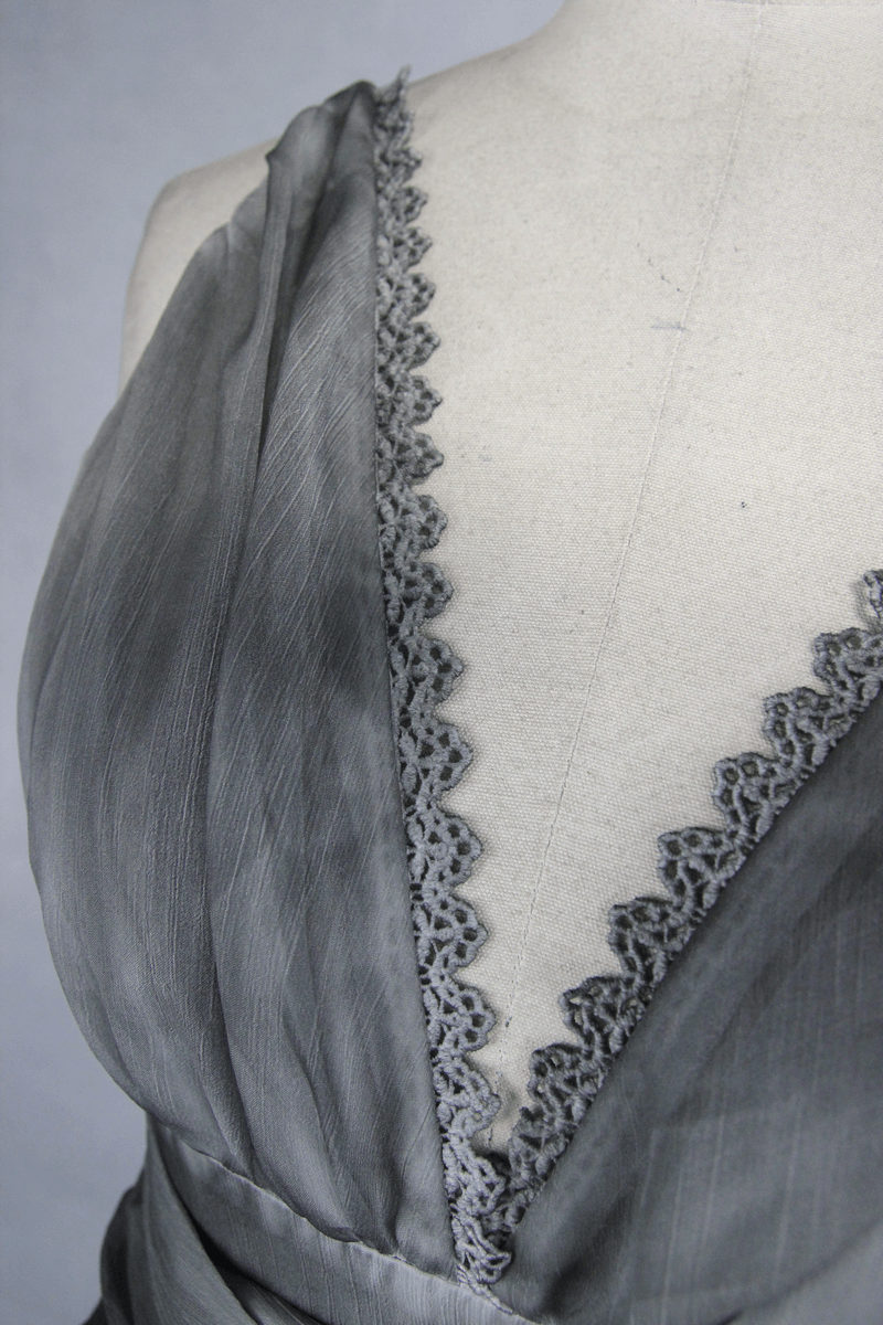 Close-up of the deep V neckline and elegant lace trim of a gothic gray women's backless dress.