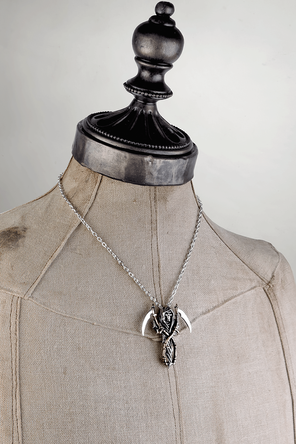 Gothic Grim Reaper pendant necklace with dual scythe design displayed on a mannequin.