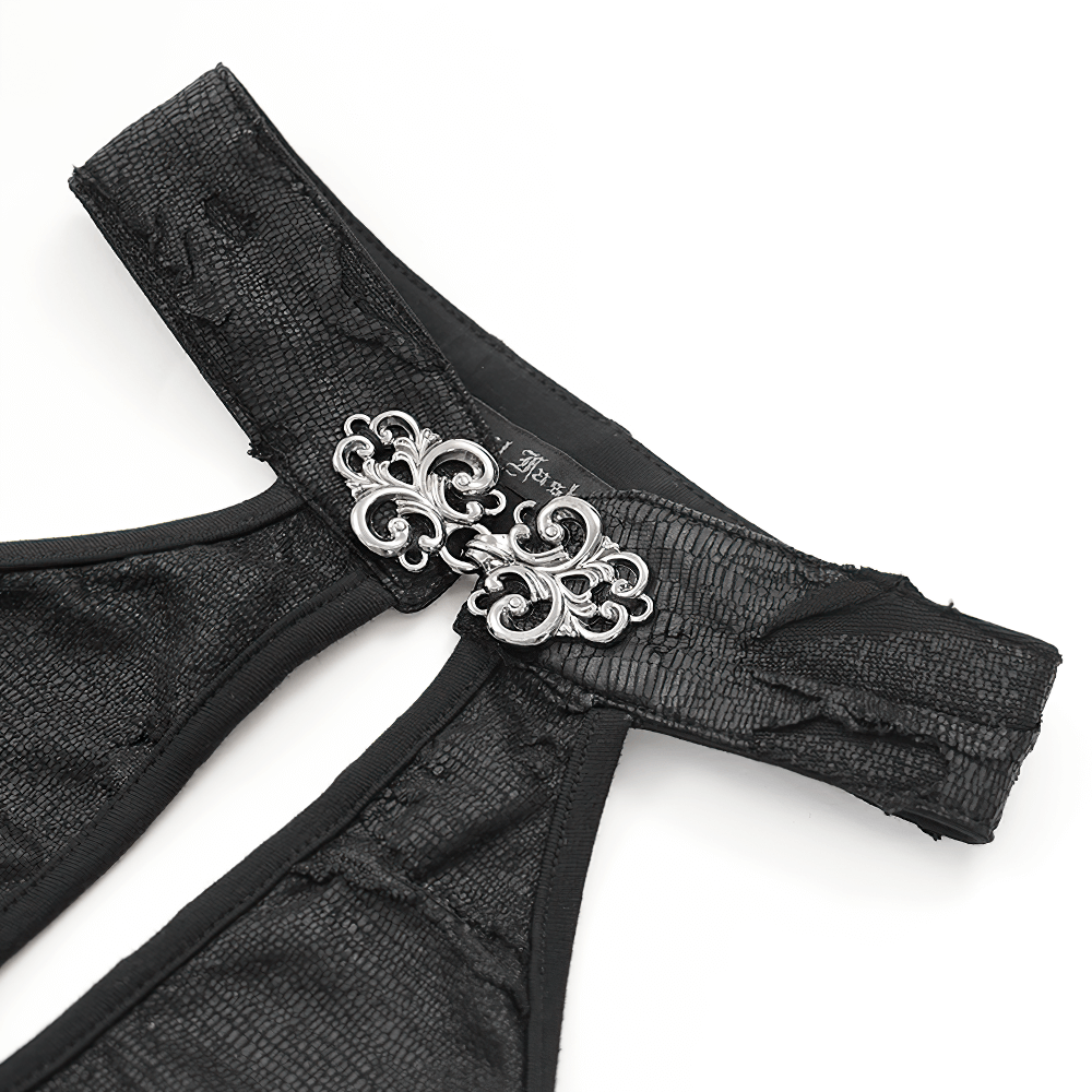 Close-up of gothic halter dress neckline with ornate cross-shaped metal embellishments and textured black fabric.