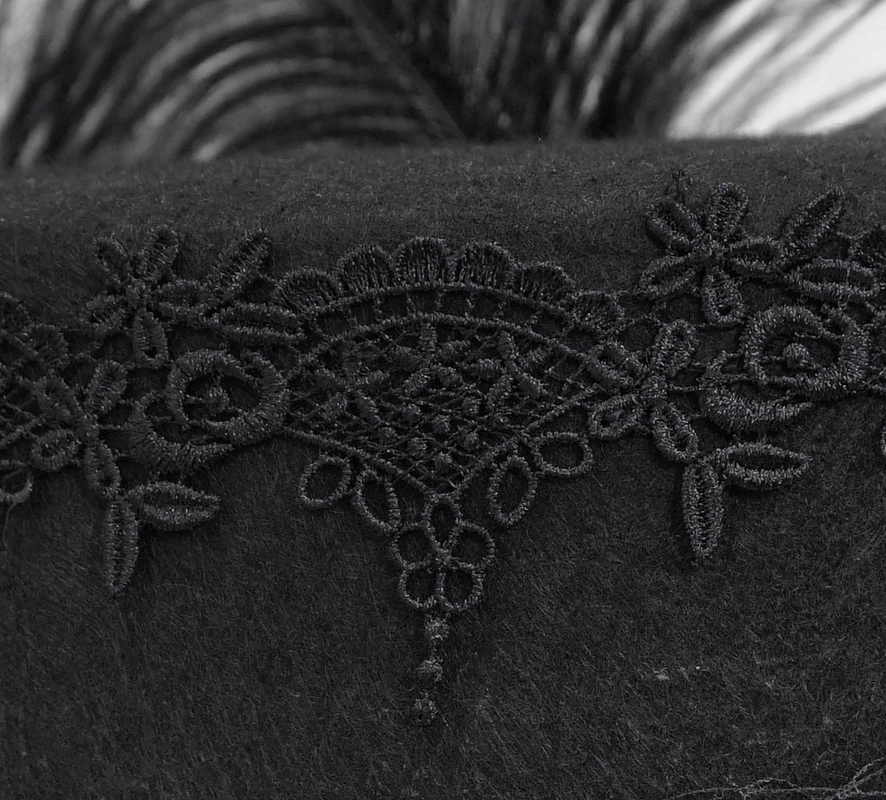 Close-up of intricate black lace embroidery on a gothic hat, showcasing vintage floral patterns.