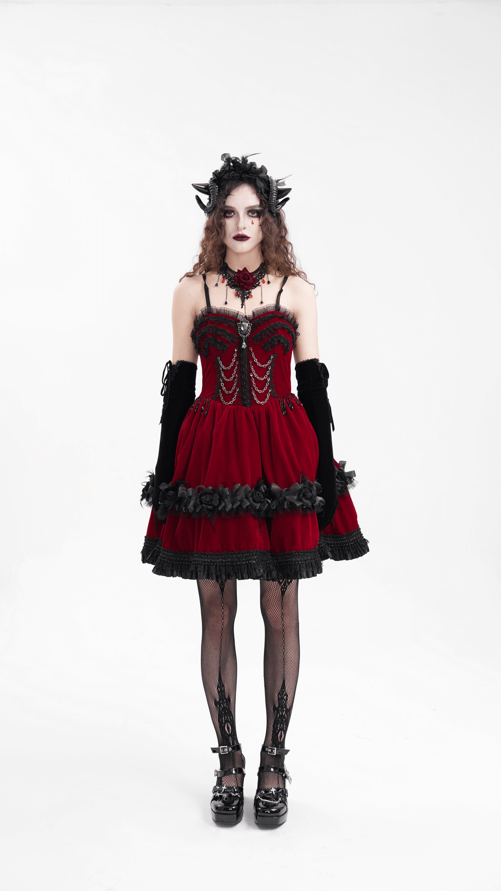 Gothic model in a red dress with black accents, featuring horns, gloves, and dark makeup for a dramatic look.