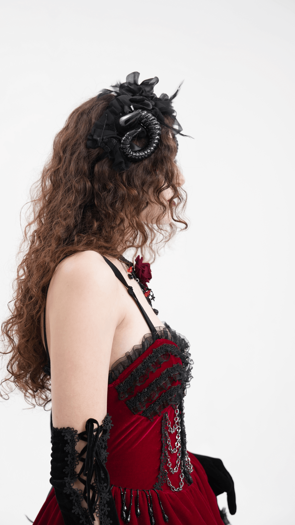 Gothic headpiece with curled horns and floral accents, paired with a red dress, embodying dark elegance.