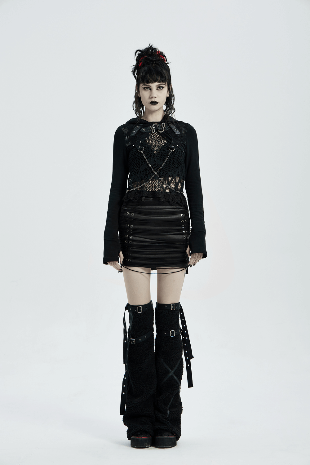 Gothic model in a punk-inspired outfit featuring a knitted chain top and dramatic layered elements.