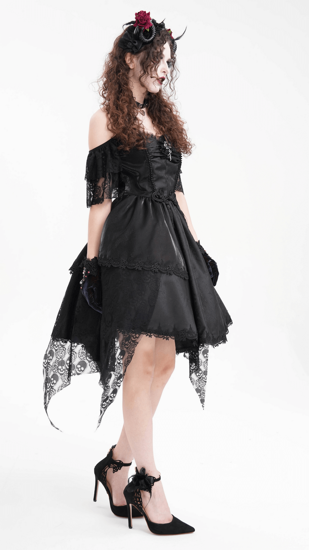 Model in a gothic black dress with lace details, wearing a horned headpiece with red roses and black ribbons.