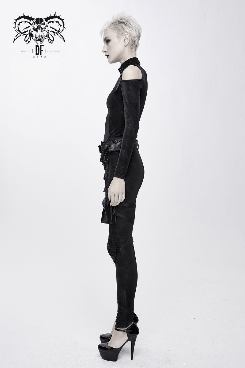 Side view of a model in a gothic black jacket with open shoulders and sleek black pants, showcasing a trendy edgy style.