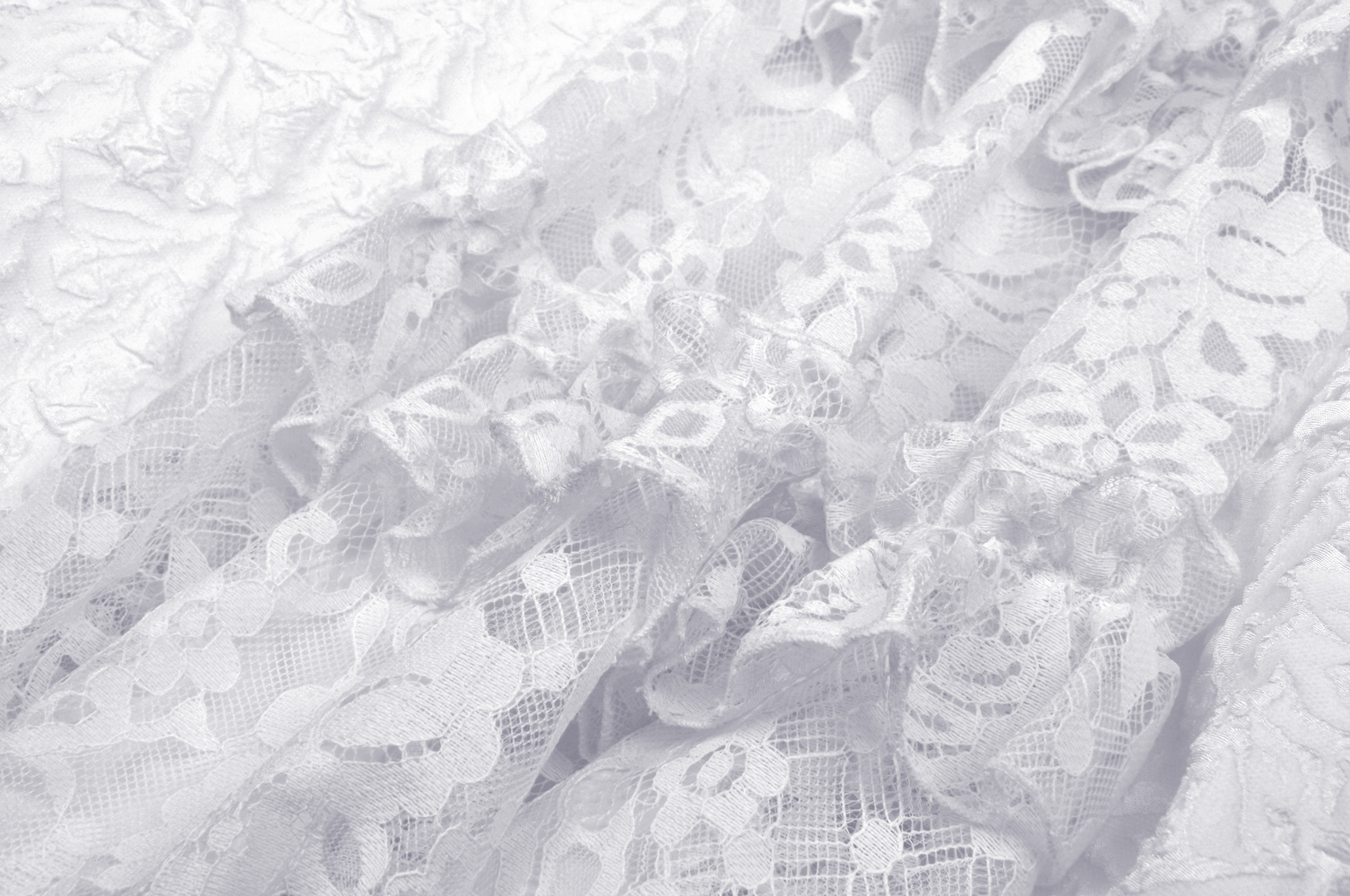 Delicate white lace fabric with intricate floral patterns, showcasing elegant texture and design details.