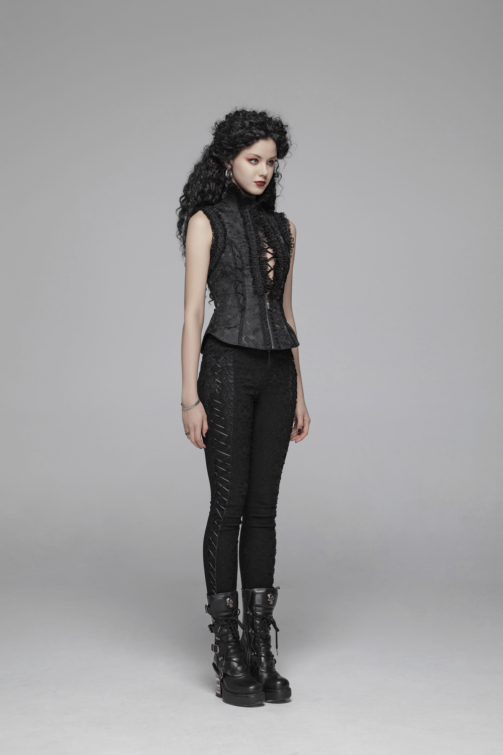 Gothic Lolita high collar waistcoat with lace detailing and zipper, paired with black skinny pants and chunky boots.