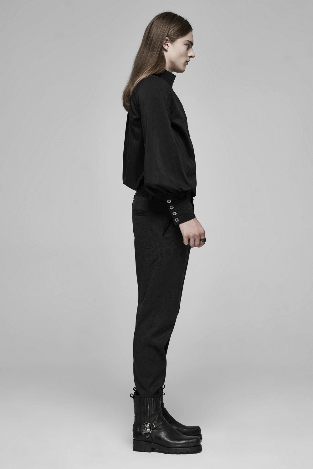 Side view of a model wearing gothic jacquard lace pants and a black blouse with metal accents.