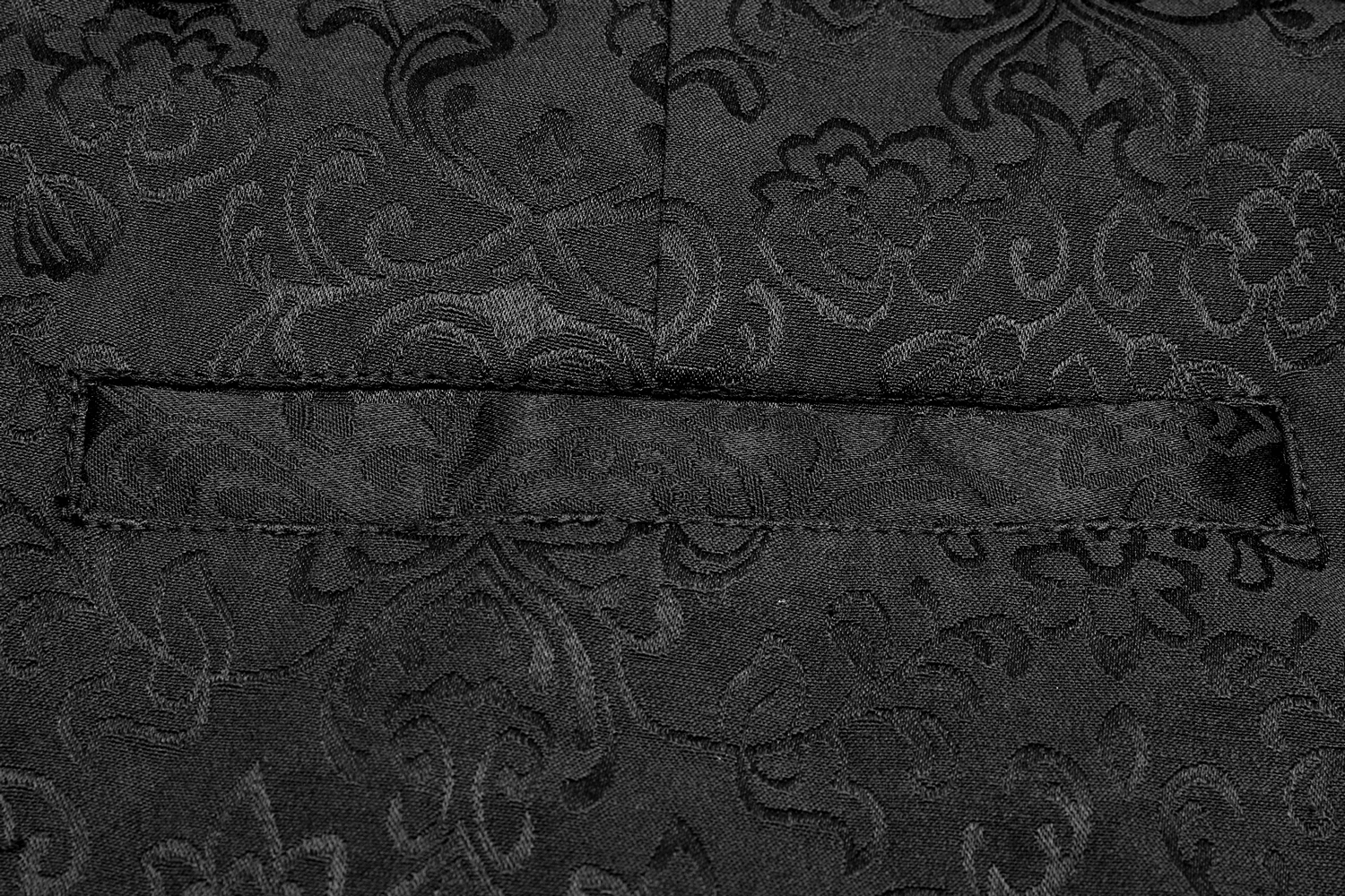 Close-up of intricate black jacquard fabric with floral patterns, showcasing luxurious texture and gothic elegance.