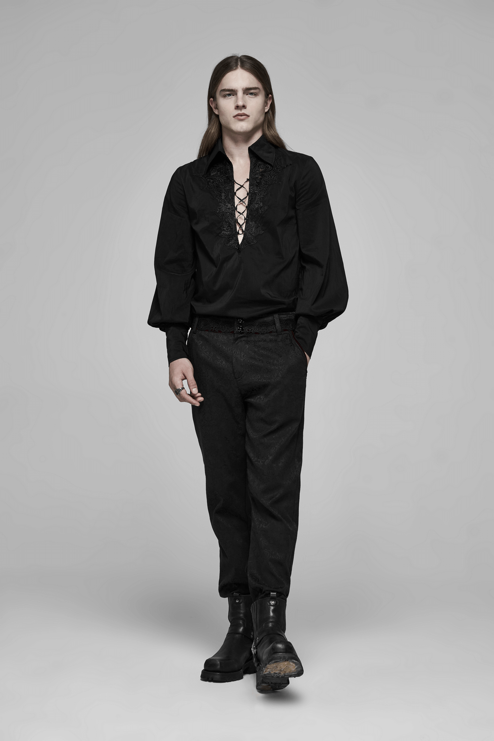 Model in black lace-up shirt and dark pants, embodying Gothic elegance with edgy fashion style.