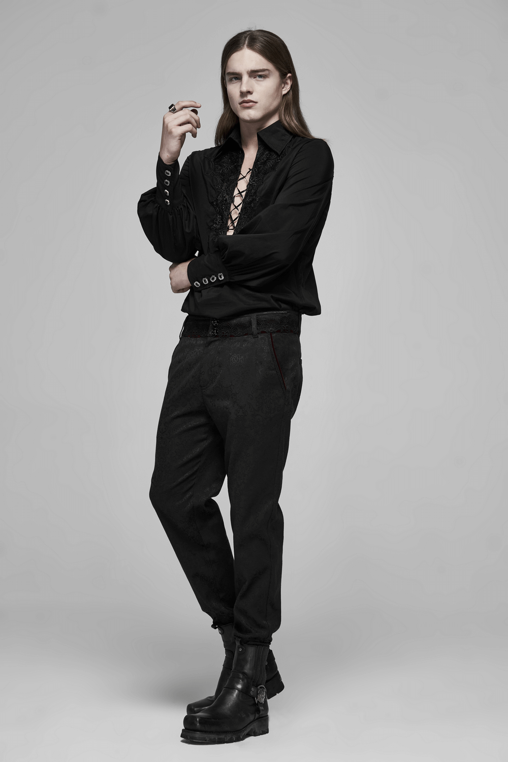 Stylish model in black lace-up shirt and dark pants, exuding gothic elegance with a modern twist.