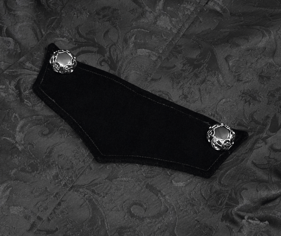 Close-up of gothic velvet coat detail featuring silver cross embellishments and intricate damask fabric design.