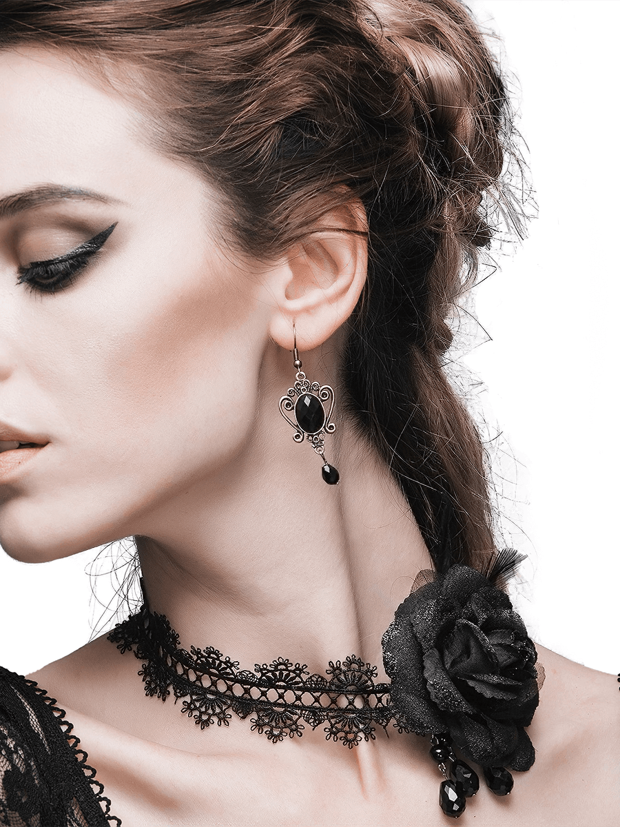 Gothic lace and rose black choker worn by a model, paired with elegant earrings, highlighting vintage fashion style.